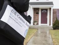 A census worker with a bag that says "U.S. Census" approaches a house