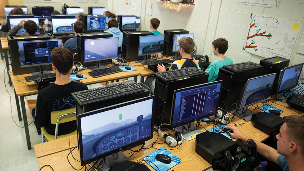 Rows of students in a classroom with their computers