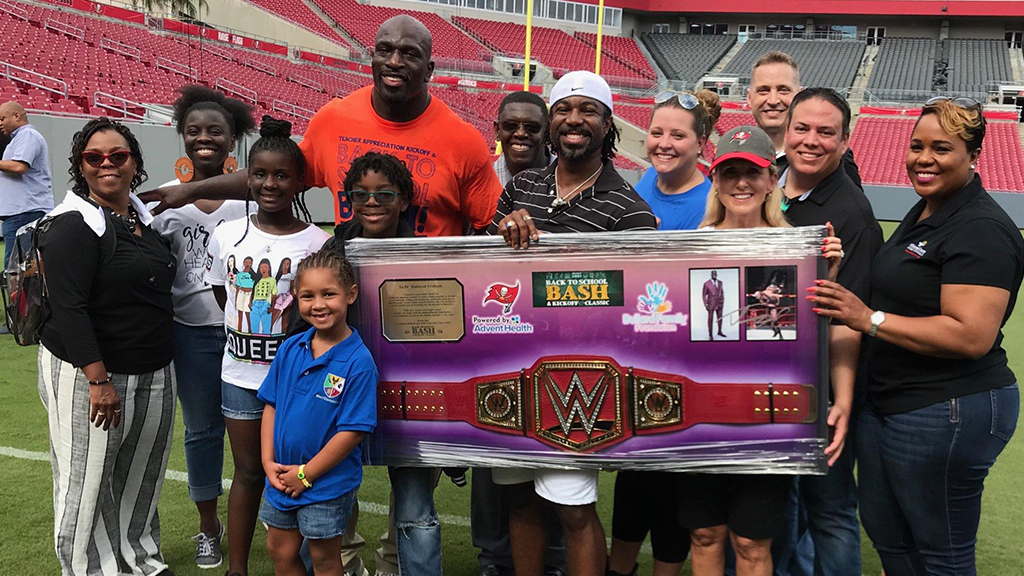 Wresting Star Titus O'Neil and community members hold up his wresting belt