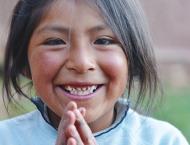 a native american girl with her hands clasped together smiles