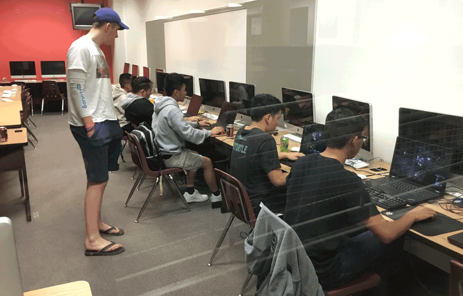 students play esports while an adult watches