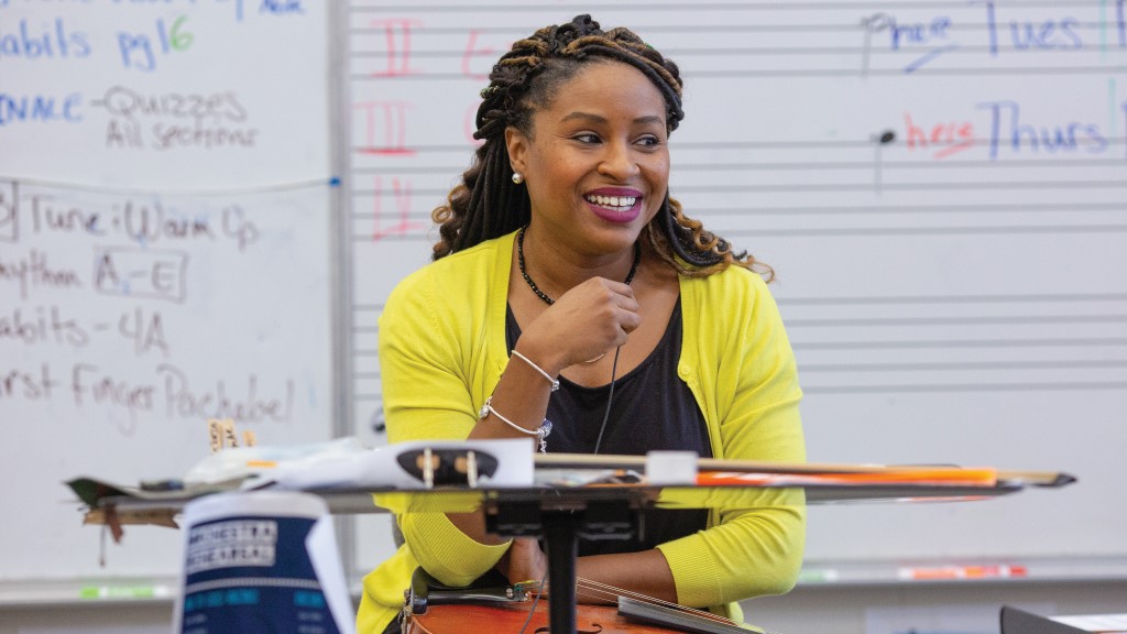 a black female music teacher smiles at her students out of frame