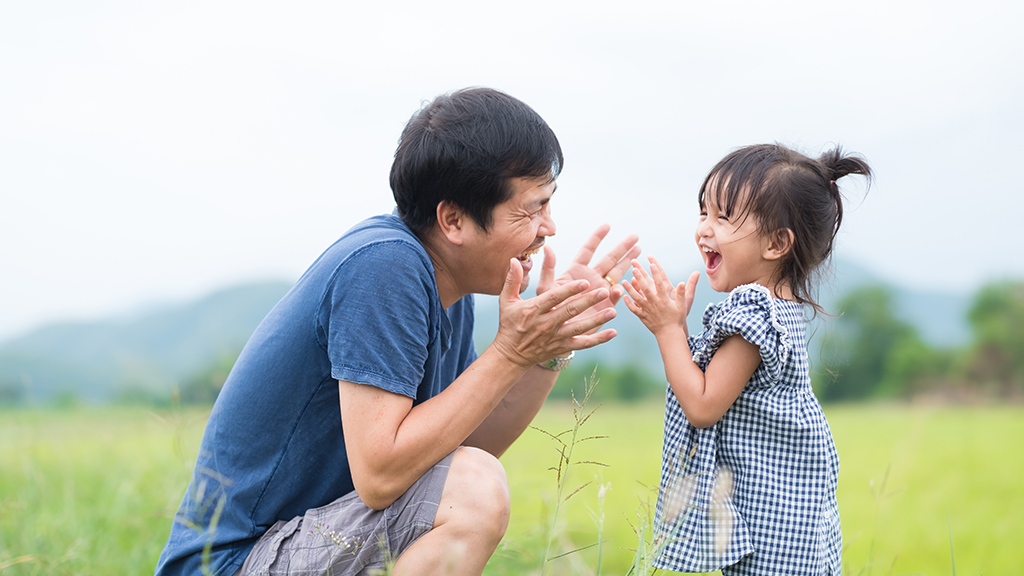 an asian american father plays with his daughter outside