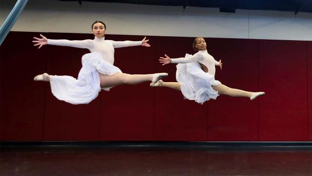 two dancers mid-leap