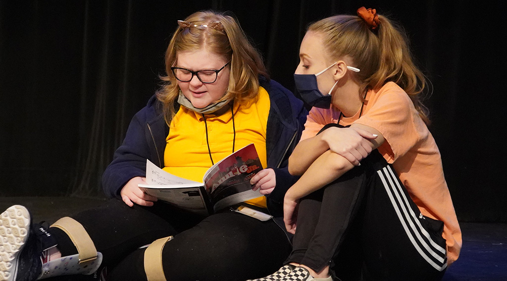 Two girls read the script for the play Annie, Jr.