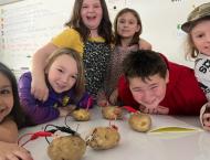 Six students conduct a science experiment with potatoes and electrodes.