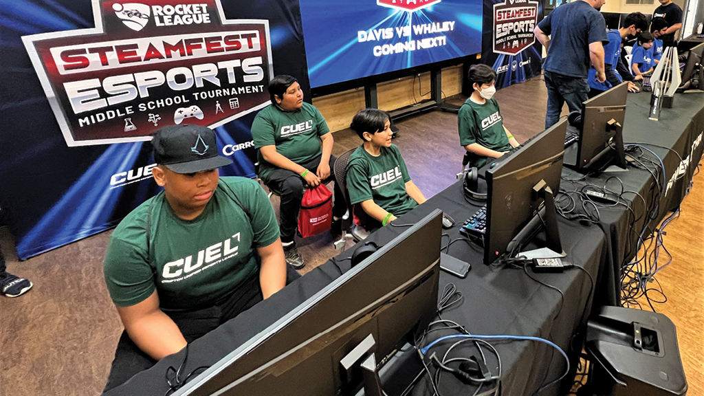 Students sit in front of a row of computers during an esports competition. 