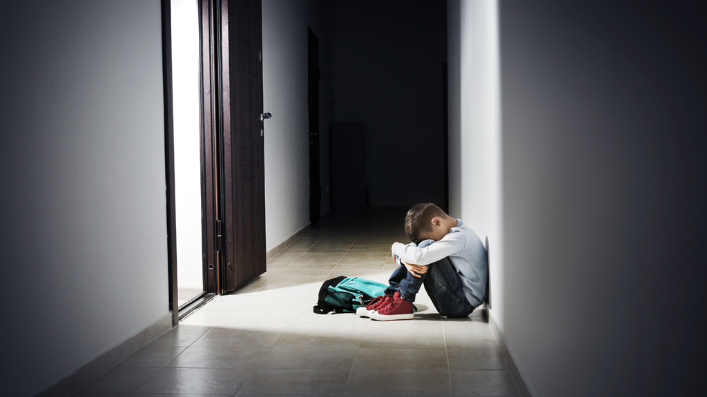 A kid curled up in a dark hallway